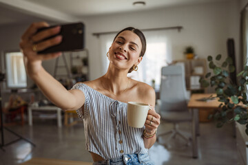 smiling woman take a self portrait on mobile phone hold coffee cup
