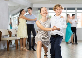 Teen guy and girl perform movements and dance hustle in pairs under guidance of woman coach....