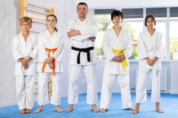 Portrait of male karate or judo coach with her students children in the gym