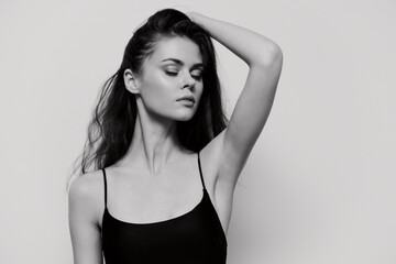 Elegant woman in black attire posing gracefully against a soft gray background, exuding confidence...