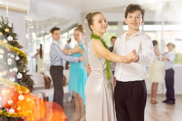 Couples dancing - teenagers in festive clothes dance the Viennese waltz near the Christmas tree