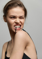 Young woman with an expressive face biting a strap, showcasing attitude and confidence. Minimalist...