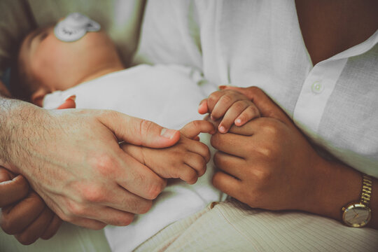 Father and mother holding baby feet - Family and newborn concept with mom and dad staying with daughter at home