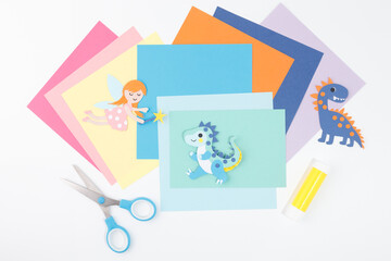 Top view of colorful DIY paper craft supplies with fairy and dinosaur figures for kids craft kits, education tools, teacher content, art brand visuals, and online course graphics,