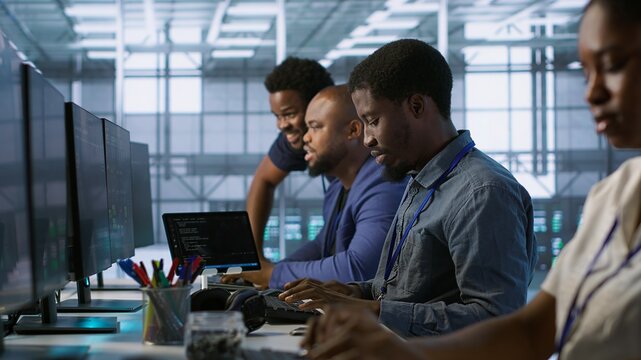 Cheerful server room workers laughing together in office while ensuring minimal downtime. Jolly engineers having fun in data center, using data analytics to monitor performance, camera A