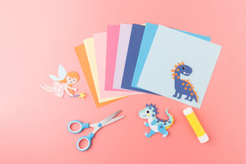 Flat lay of kids craft supplies with fantasy dragons on pink background, perfect for DIY tutorials,...