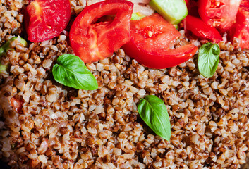 Healthy food without meat with buckwheat and a salad of chopped tomatoes, cucumbers, onions and basil leaves. The photo is suitable for the topic of healthy lifestyle and healthy eating