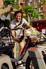 Happy businessman using phone app for urban mobility, renting a shared electric bicycle with...