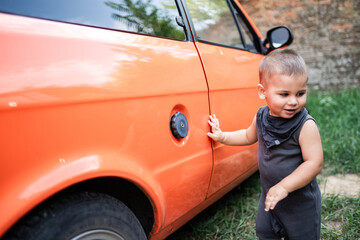 Toddler exploring orange vintage car outdoors