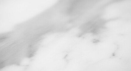 Abstract close-up of white marble stone surface with subtle gray veining, creating a soft, textured background.