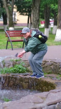 Woman playing with water from a fountain in a city park. 4k video.