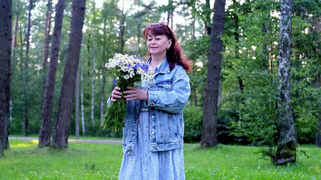A woman holds a gift in her hands - a huge bouquet of wild flowers. daisies and cornflowers. Video 4k.