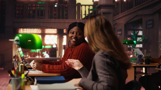 Mature woman student in the library highlighting important ideas for exams, focusing on her studies surrounded by academic materials and books. Study strategy memorization. Camera B.