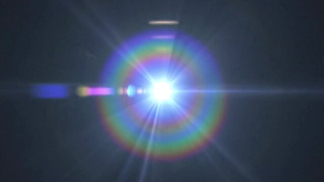 A bright central light source surrounded by a rainbowlike halo with linear light rays extending outward