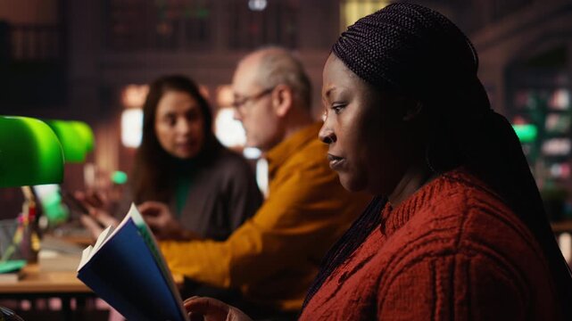 Annoyed woman asking people to keep the library rules and be quiet, polite request to maintain the silence. Mature colleagues studying together for exam, reading materials out loud. Camera B.