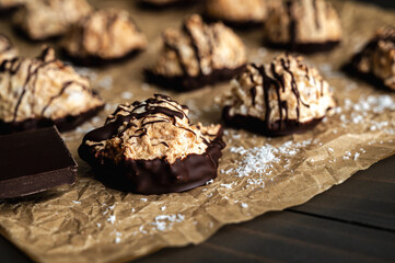 Macaroons Drizzled with Dark Chocolate on Unbleached Parchment Paper: Toasted coconut meringue drop cookies dipped in bittersweet chocolate close-up