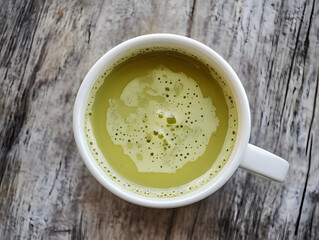 A frothy cup of matcha tea on a rustic wooden surface