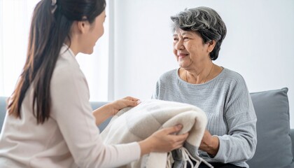毛布をかける女性と微笑む高齢女性
