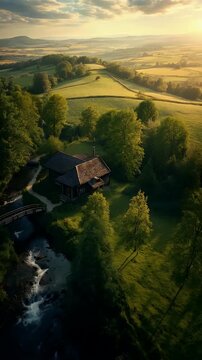 Aerial View of Rustic Cottage and Wooden Bridge by Mountain Stream at Sunset
