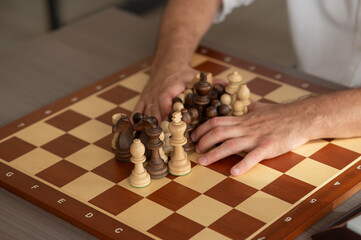 Close up of hands of middle aged caucasian man playing chess. 