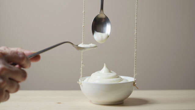 Mayonnaise in Bowl and Spoons Suspended by Twine