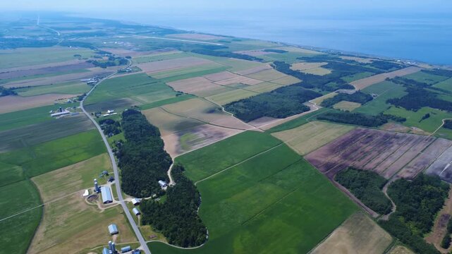 Panoramic aerial view of the municipality of Price and agricultural fields along the St. Lawrence River in the La Mitis region, smoky from Canadian forest fires, Quebec, Canada, 2025.