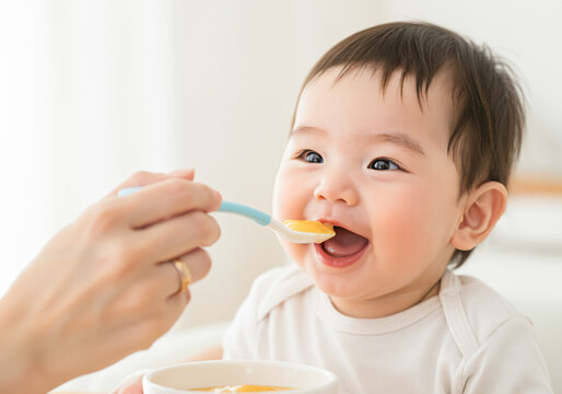 お母さんから離乳食をもらい嬉しそうに口を開ける赤ちゃん