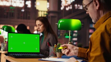 Focused senior man reading academic text with chroma key on pc at the university, sitting in vintage study area and browsing online coursework. Knowledge and ambition. Camera B.