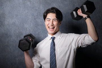 ダンベルで筋トレするスーツの男性...