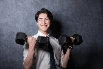 ダンベルで筋トレするスーツの男性...