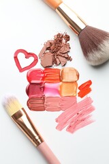 Different cosmetic products and makeup brushes on white background, flat lay