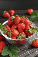 Fresh ripe strawberries and leaves in container on table, closeup