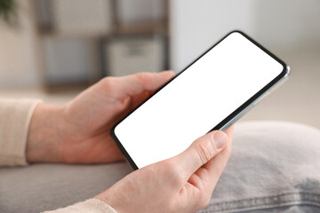 Woman using modern smartphone at home, closeup