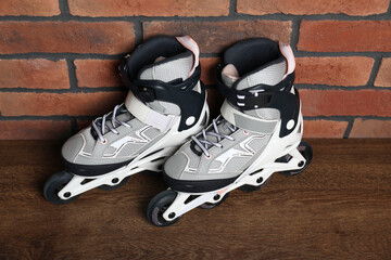 Pair of roller skates on wooden table near brick wall