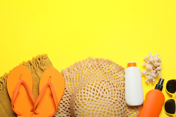 Flat lay composition with beach towel and other summer accessories on yellow background. Space for...