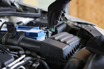 Auto parts. Professional mechanic with screwdriver fixing car indoors, closeup