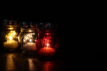 Many grave candles on black background, closeup. Space for text