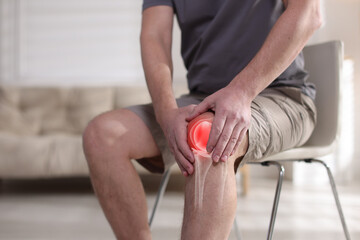 Arthritis. Man suffering from knee pain indoors, closeup. Illustration of joint inflammation on his...