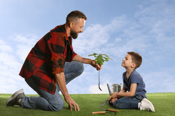Father and his son planting tree into ground outdoors