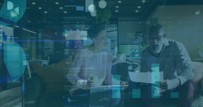 Sitting colleagues reviewing charts on sofa in office lounge, with coffee cups and data overlay