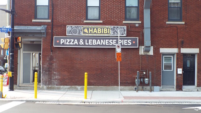 Ottawa, ON, Canada-July 12,2025 : An image of a storefront with a sign that says "HABIBI" and below it "PIZZA and LEBANESE PIES "at 62 Main Street. 