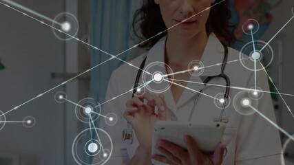 Doctor tapping tablet as loading circle pulsing, guiding network overlay during health data review - Powered by Adobe