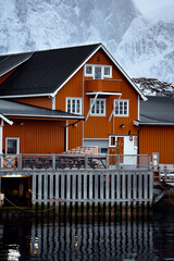 A Charming Orange House Nestled by the Water Surrounded by a Beautiful Snowy Landscape