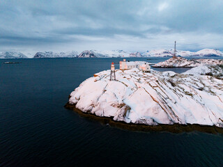 A serene winter landscape featuring a lighthouse situated on a snowy, isolated island
