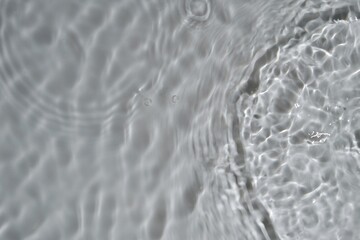 Top view shining water ripples texture. Transparent clear calm water surface texture with splashes and bubbles. White grey water waves in sunlight. Trendy abstract nature background.