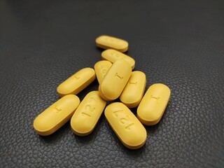 Yellow pills on black leather surface
