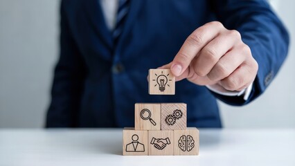 Hand placing lightbulb block on stack representing business concepts
