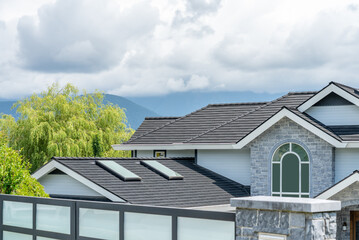 Fototapeta premium Top of grey stucco luxury house with shingle roof, green trees and nice windows in Spring in Vancouver, Canada, North America. Day time on May 2025.