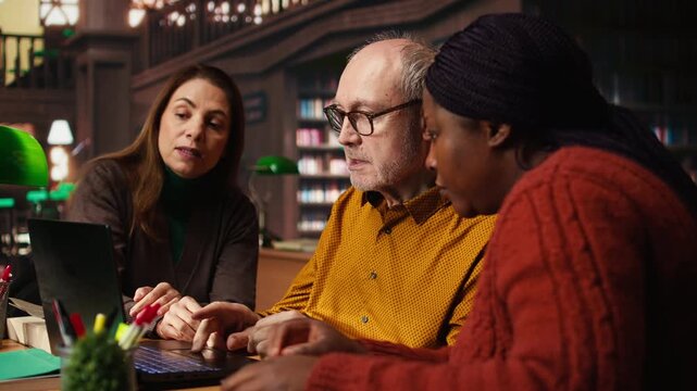 Adult students examines information during a lecture in a university library, surrounded by academic textbooks and archived documents or materials. Personal goals on campus. Camera A.