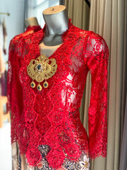 Red Lace Kebaya with Batik Skirt and Ornate Gold Brooch on Mannequin